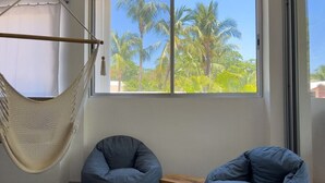 Een kamer met twee grijze schapenvachtzitjes, een hangmat en een raam met uitzicht op palmbomen.