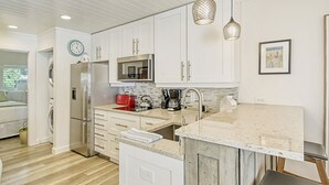 A modern kitchen with white cabinetry, stainless steel appliances, a built-in microwave, and pendant lighting. - Homey 1bed/1bath condo The Meadows Pool View (Sarasota)