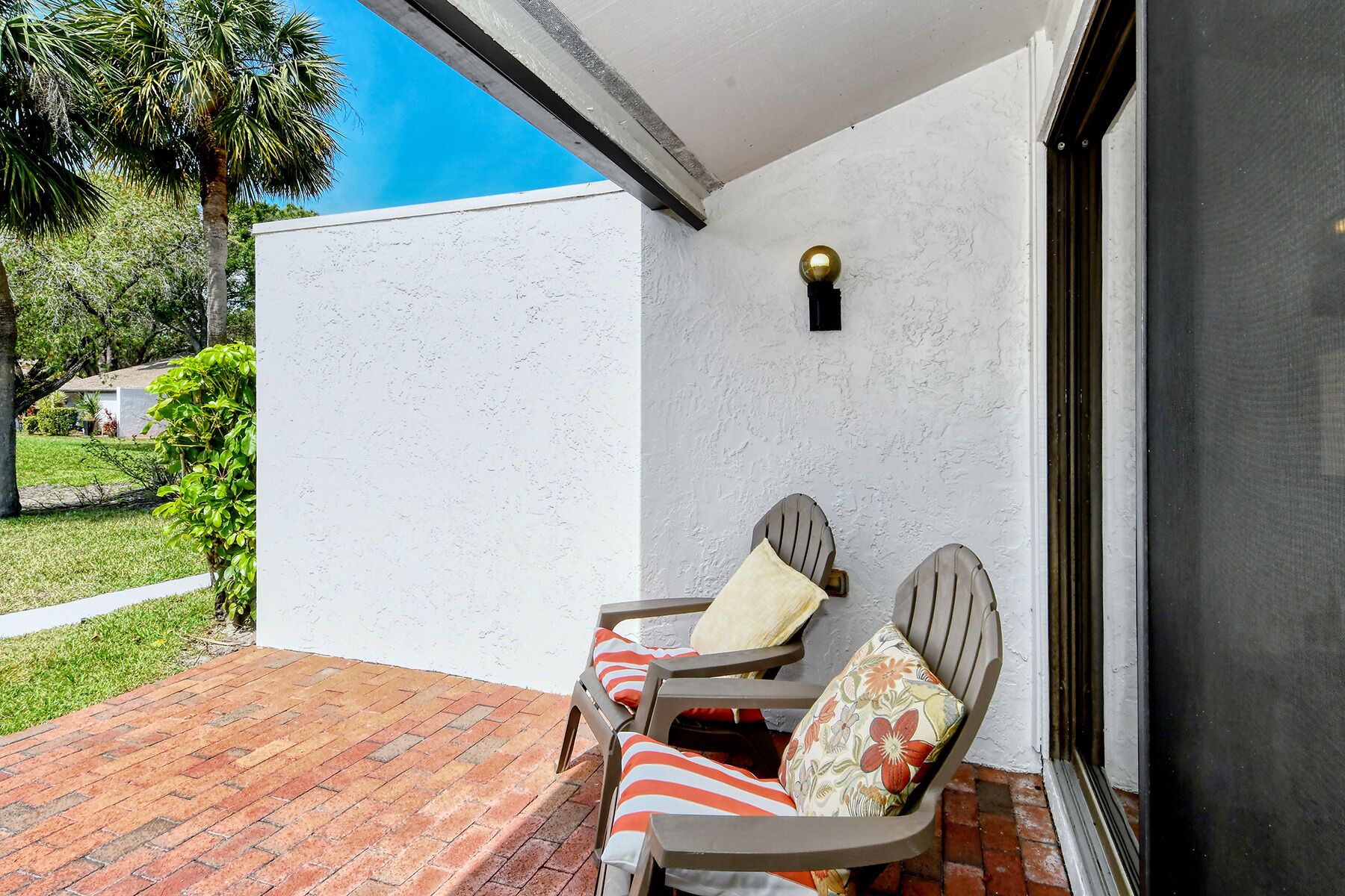 Une terrasse avec deux chaises et une table, des murs blancs et un ciel d’un bleu éclatant.