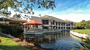A waterfront property with a covered patio area, a pool, and a well-maintained lawn. - Homey 1bed/1bath condo The Meadows Pool View (Sarasota)