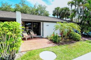 A single-story house with a covered porch, a brick patio, and a well-maintained lawn.