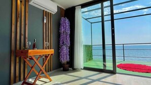 A room with a wooden table, a potted plant, and a view of the sea through large windows. - Ada Tiny House (Ayvacik)
