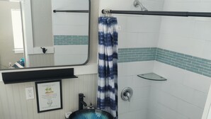 A compact bathroom with a toilet, sink, and shower.
