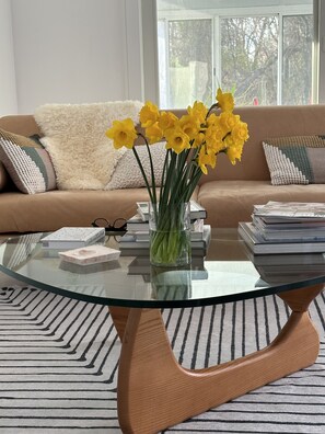 A living room with a glass coffee table, a sofa, and a vase with yellow flowers. - Palm Springs Vibes on the North Fork (Southold)