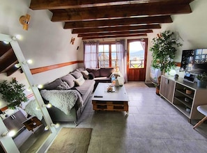 A cozy living room with a sofa, coffee table, and a TV. There are plants, a mirror, and a wooden ceiling. - Ushuaia Magnifica (Ushuaia)