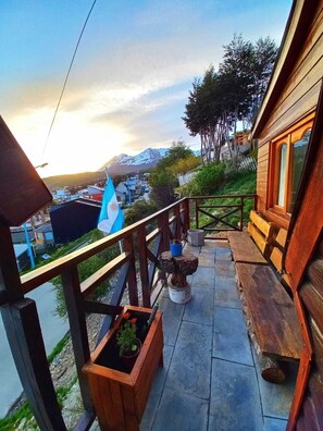 A wooden balcony with a view of a mountain and a flag.