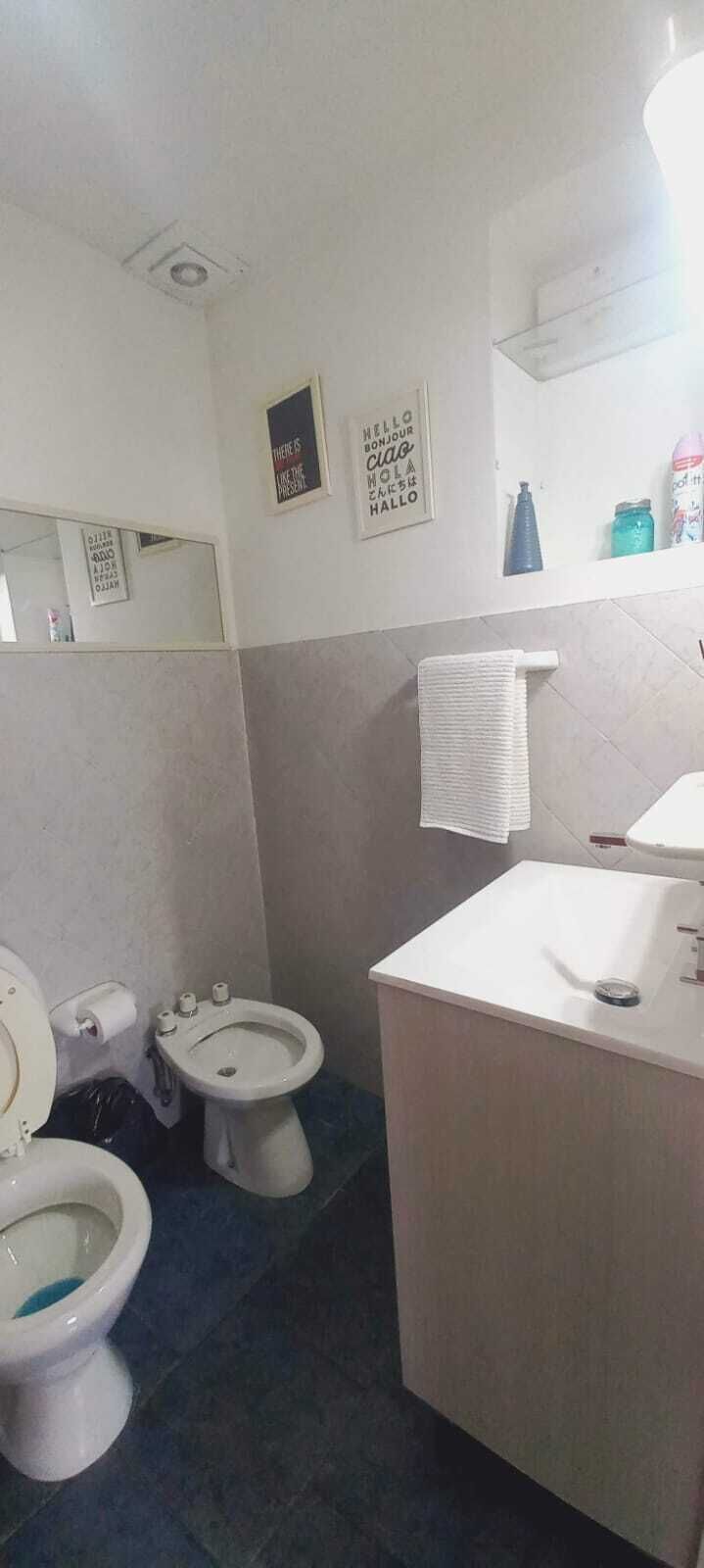 A bathroom with a toilet, bidet, and sink. There are towels hanging on a rack, and a mirror on the wall.