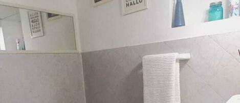 A bathroom with a toilet, bidet, and sink. There are towels hanging on a rack, and a mirror on the wall.