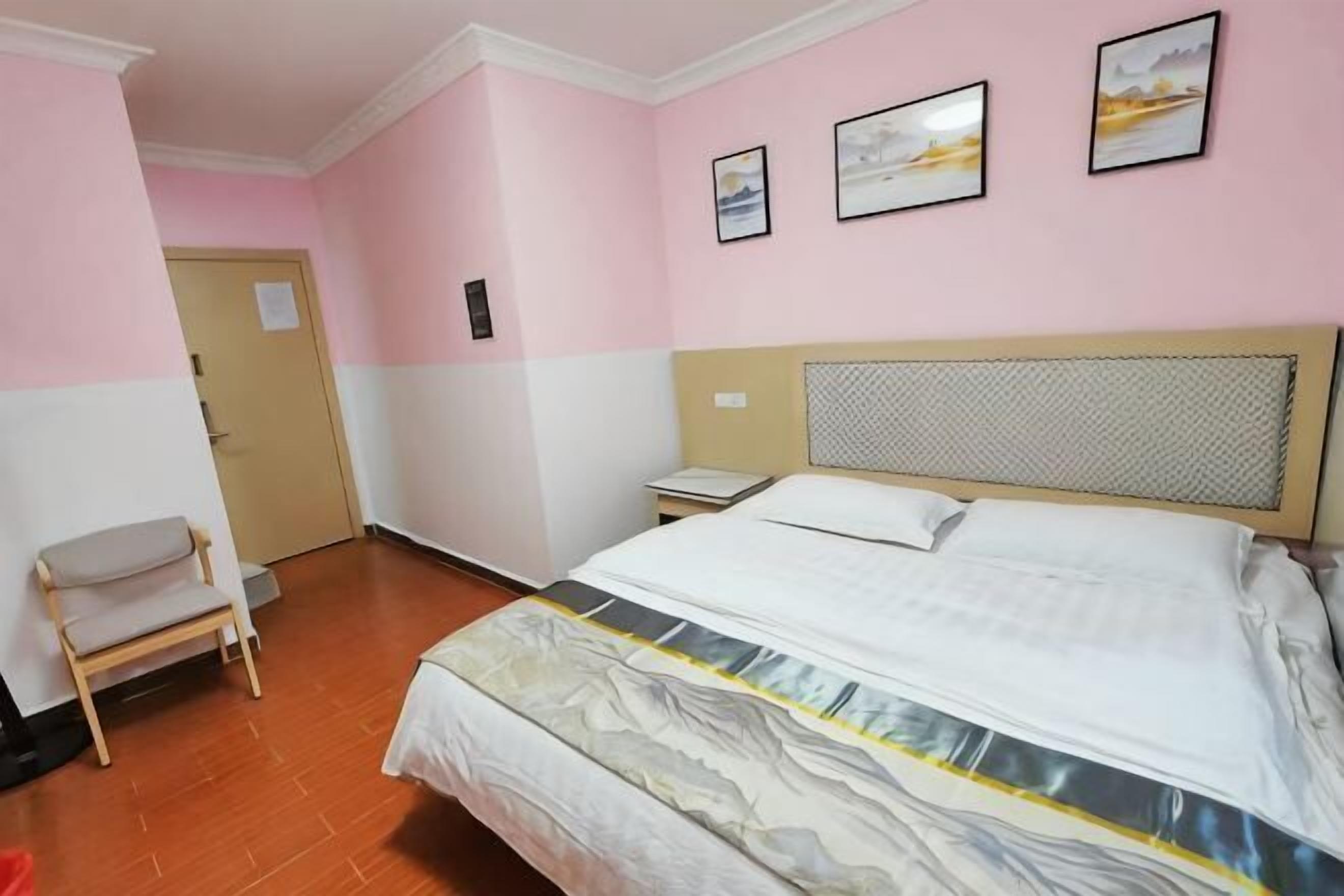 A bedroom with a bed, a chair, a nightstand, and a door.