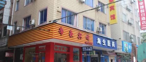 A building with a red and yellow awning, a pharmacy, and a sign for a hotel.