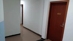 A corridor with a tiled floor and a wooden door with a number plate. - Guilin Dihao Hotel (North Railway Station Branch) (Guilin)