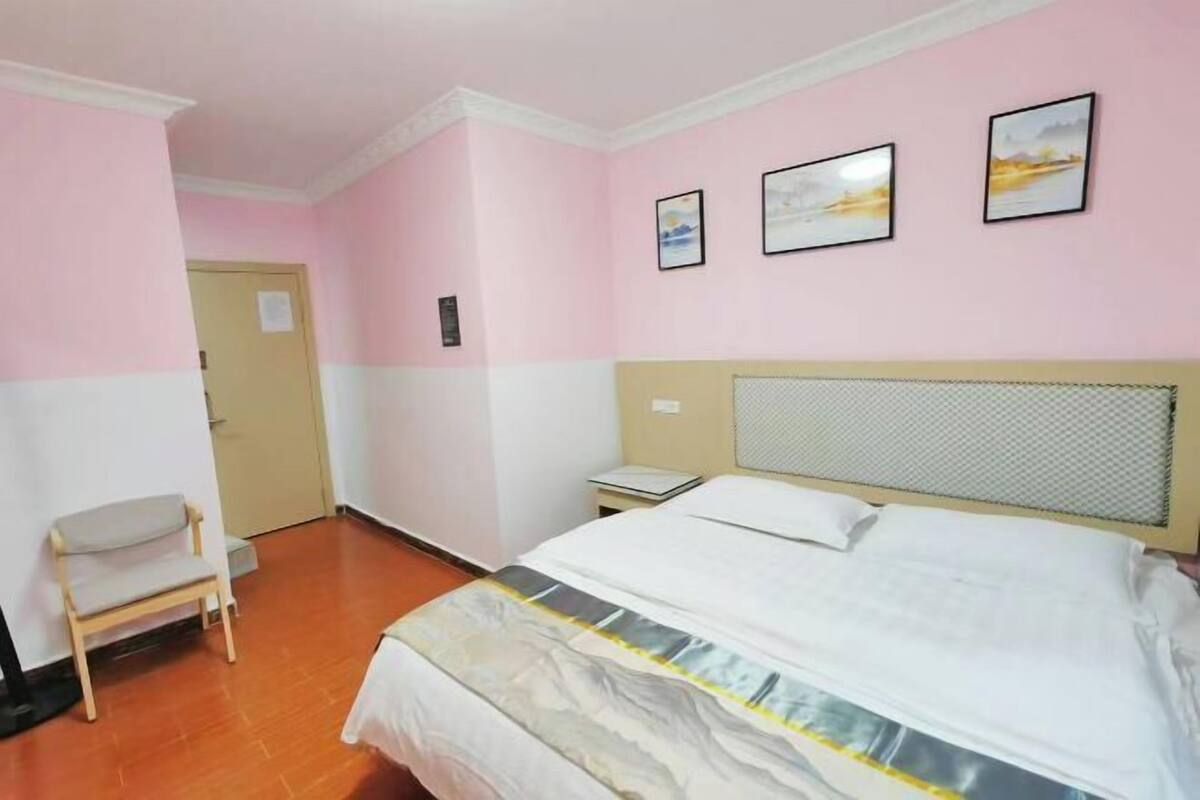 A bedroom with a bed, a chair, and a door.