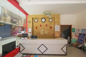A reception desk with a wooden panel, a clock, and a bulletin board. - Guilin Dihao Hotel (North Railway Station Branch) (Guilin)