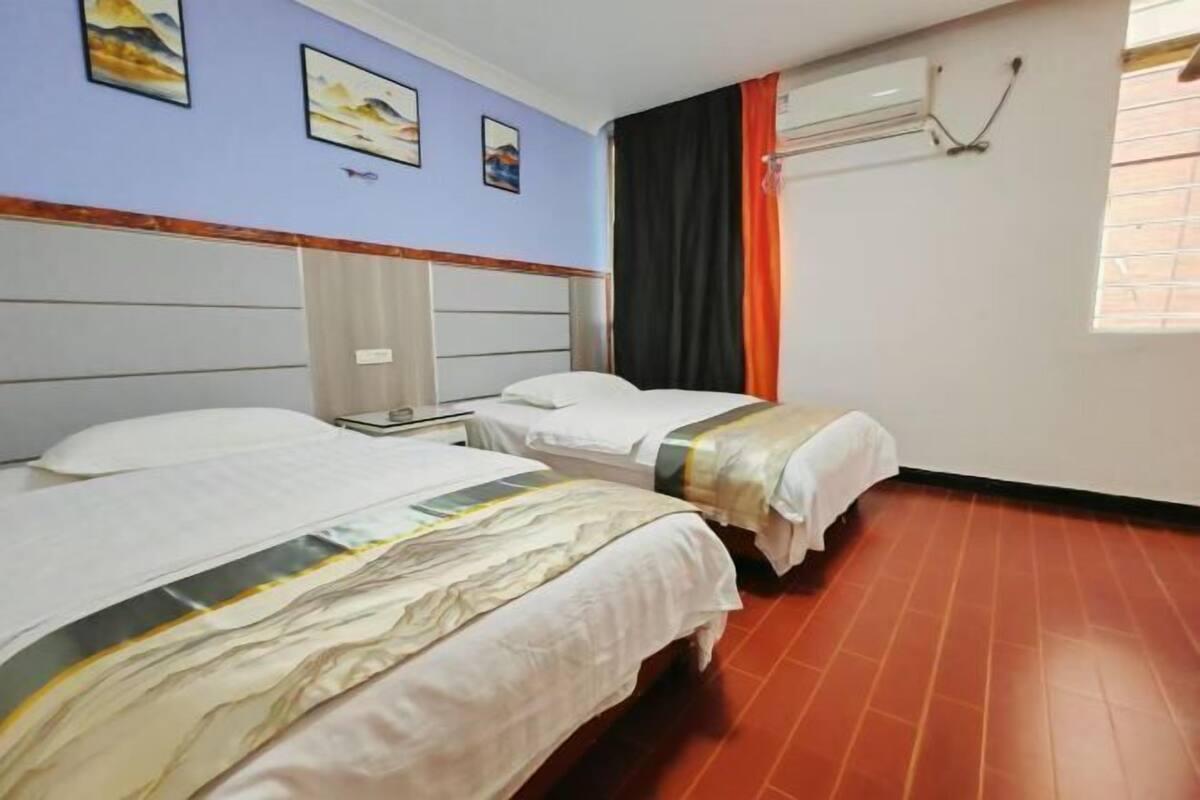 A hotel room with two beds, a window with curtains, and artwork on the wall.