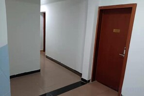 A corridor with a closed wooden door, a tiled floor, and a visible door number. - Guilin Dihao Hotel (North Railway Station Branch) (Guilin)