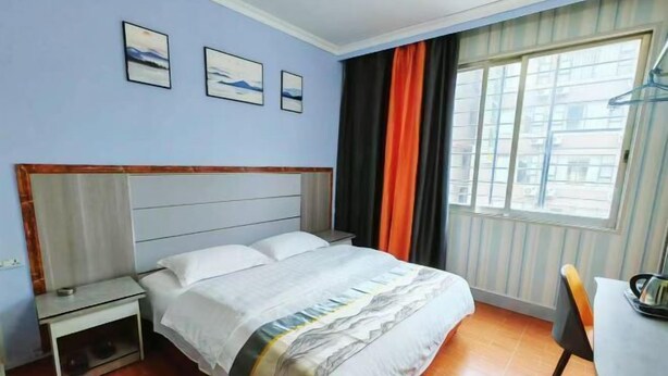 A hotel room with a bed, a nightstand, a desk, and a window with curtains. - Guilin Dihao Hotel (North Railway Station Branch) (Guilin)