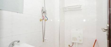 Ein kleines, sauberes Badezimmer mit Waschbecken, Dusche und Toilette.