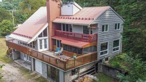 A two-story house with a balcony, a chimney, and a garage. - Beautiful cottage w/firepit, pool and a river in the property (Duclos)