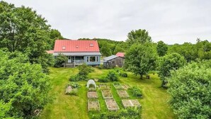Ein Haus mit rotem Dach, umgeben von üppigem Grün und einem gepflegten Rasen.