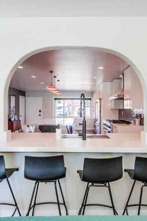 Une cuisine moderne dotée d’un comptoir en arc de cercle, de tabourets de bar et de luminaires suspendus.
