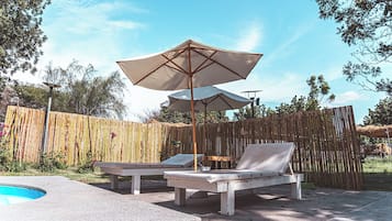 Alberca al aire libre, sombrillas en la alberca y camastros