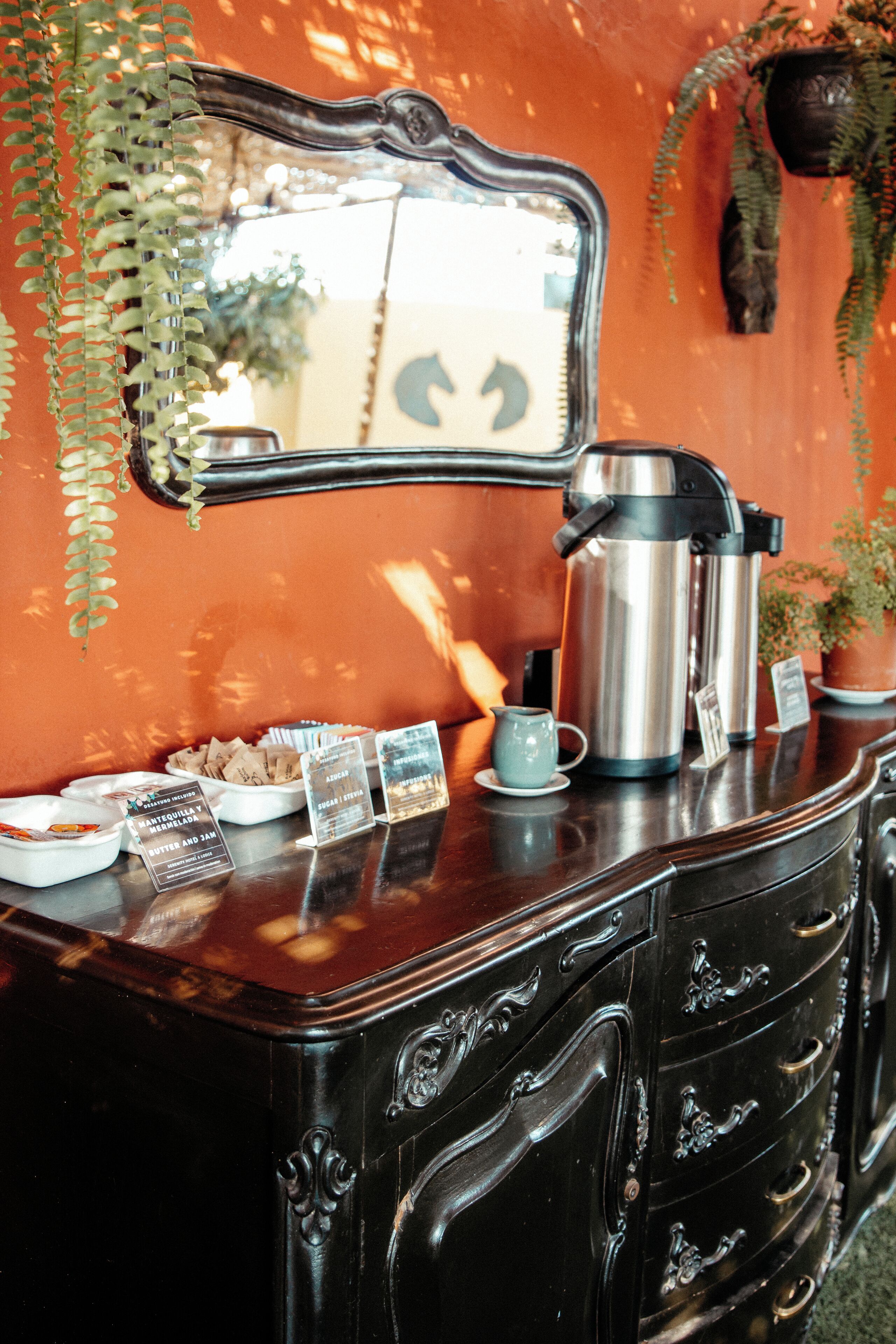 A vintage-style dresser with a mirror, a coffee maker, and a small teapot.