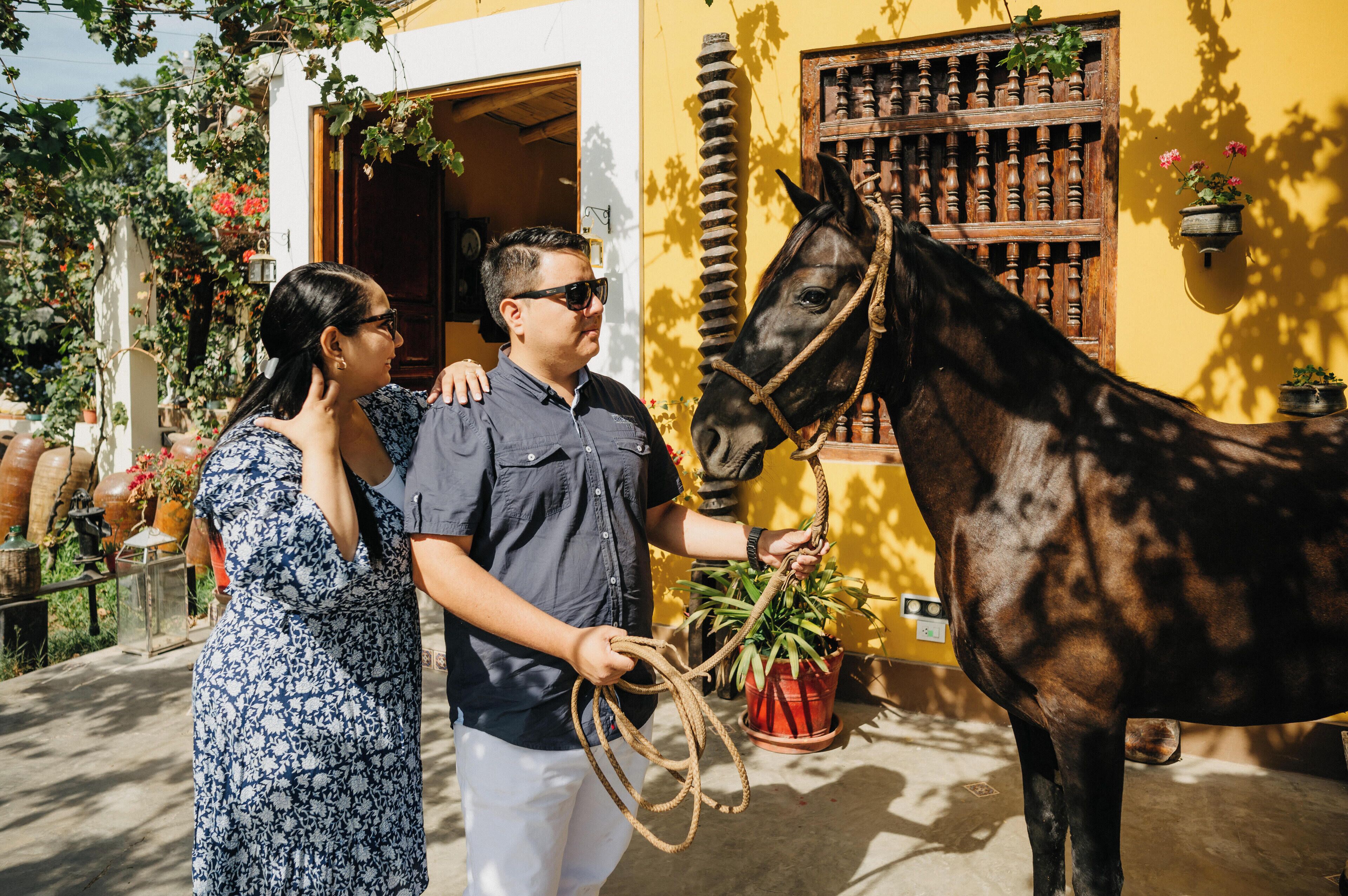 A man and a woman standing next to a horse with a rope.