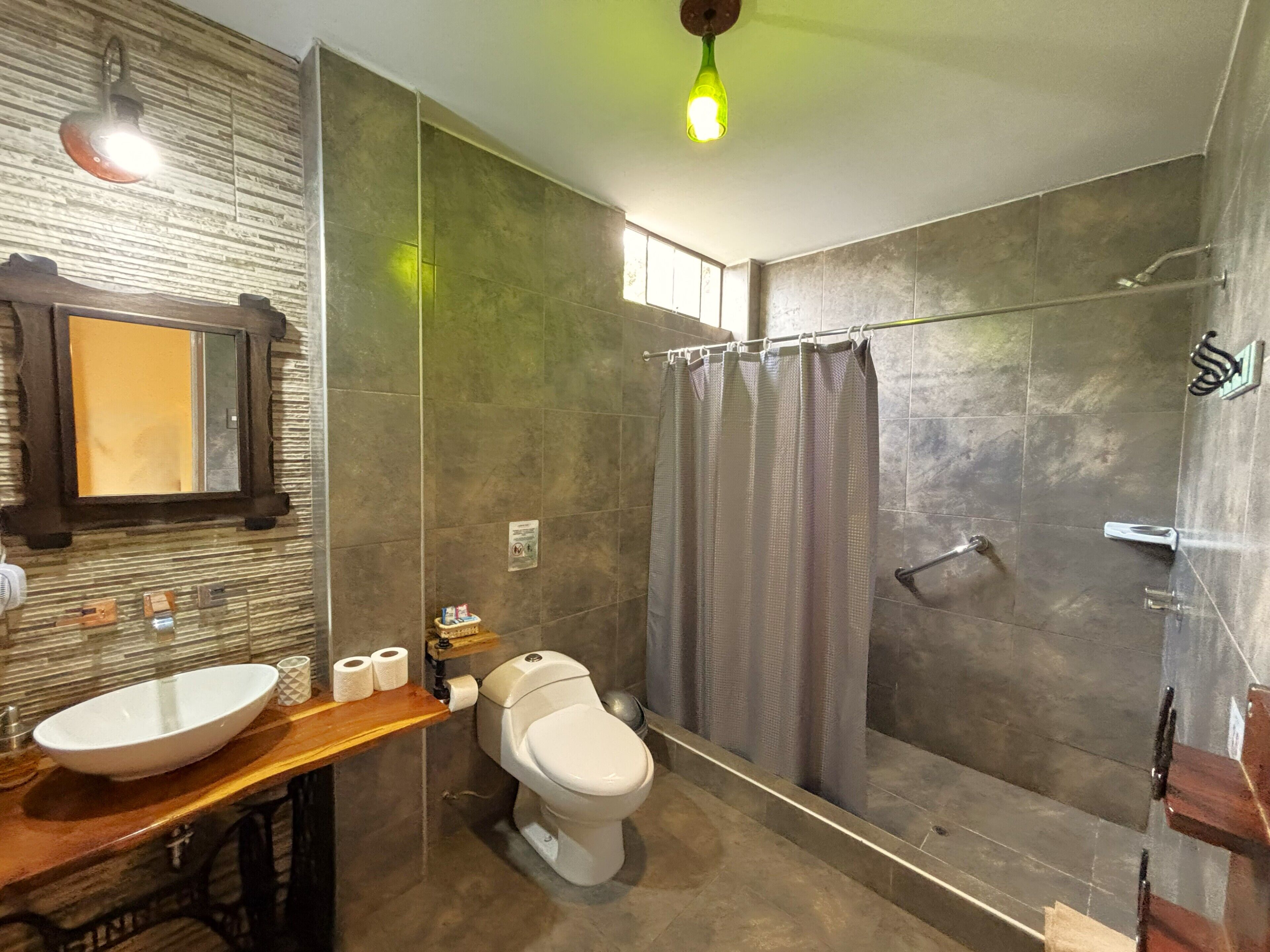 A bathroom with a large mirror, a sink, a toilet, and a shower area.