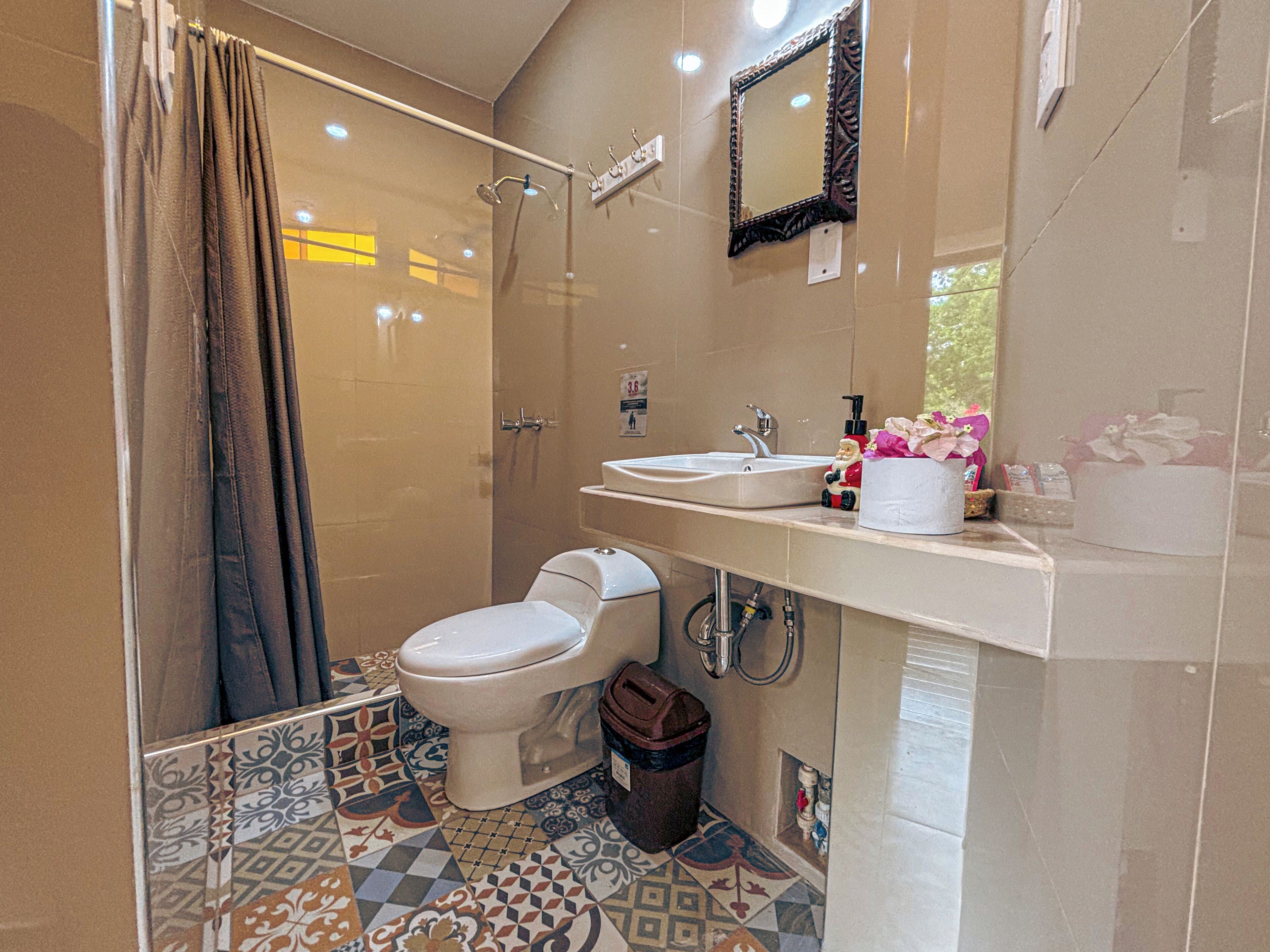 Un baño con ducha, inodoro, lavabo y espejo.