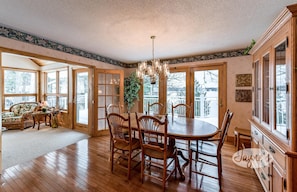 Enjoy meals in this elegant dining area with a large table and six chairs, surrounded by artwork and offering views of the surrounding landscape.