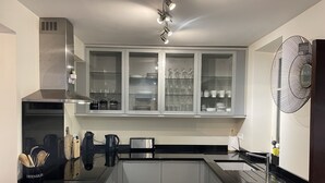Une cuisine moderne dotée d’un plan de travail noir, d’appareils électroménagers en acier inoxydable et de meubles avec des portes en verre.