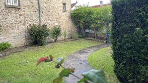 Un bâtiment en pierre avec un étroit sentier également en pierre qui mène à une zone herbeuse.