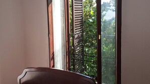 A room with a large sliding glass door leading to a balcony with a view of greenery and a fence. - Apartments Rudi - Superior One bedroom Apartment with Terrace and Sea View (Klenovica)