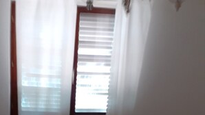 A bedroom with a bed, curtains, and a window with blinds. - Apartments Rudi - One Bedroom Apartmen with Terrace and Sea View (Klenovica)