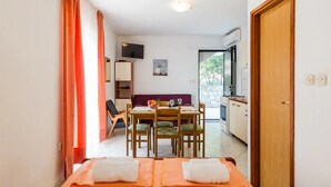 A hotel room with a bed, a dining table, chairs, a TV, and a kitchen area. - Apartments Villa Pelegrin - Studio Apartment with Sea View (Apartment (Zavala)