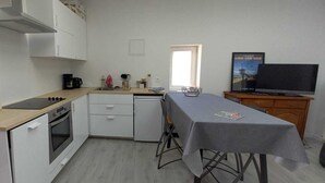 Une cuisine compacte équipée d’une cuisinière, d’un four et d’un petit coin repas avec une table et des chaises.