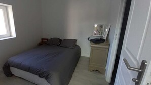 Une chambre à coucher avec un lit, une table de chevet, une commode, une fenêtre et une porte.