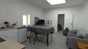 A compact living space with a kitchenette, a dining area, and a seating area with a sofa and a table. - An apartment with your feet in the sand (Lion-sur-Mer)
