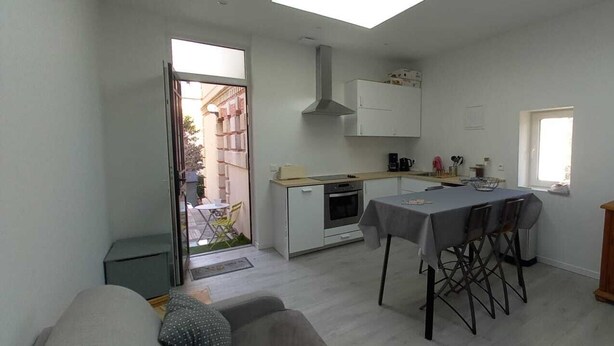 Une cuisine compacte avec un coin repas, un téléviseur posé sur un meuble en bois et une fenêtre ornée d’une affiche.