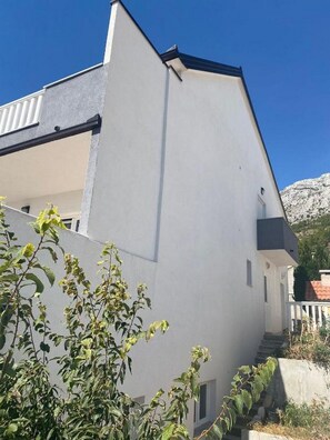 Un edificio moderno con facciata bianca, tetto spiovente e una scala a vista che conduce a un piano superiore.