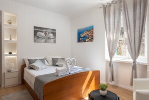 A modern bedroom with a wooden bed, white bedding, and two wall art pieces.