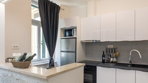 Een moderne keuken met witte kasten, een roestvrijstalen koelkast, een inbouwoven en een zwart aanrecht.