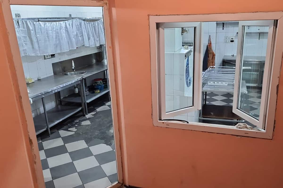 A kitchen with stainless steel countertops, a sink, and a tiled floor.