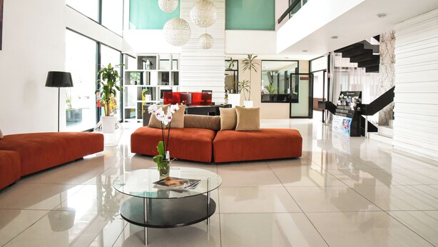 Amplia sala de estar moderna con una mesa de centro de vidrio, sofás naranja e iluminación decorativa.