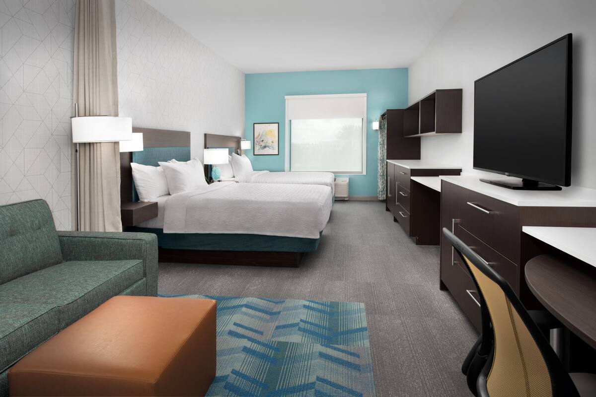 Een moderne hotelkamer met een groot bed, een bank, een bureau en een televisie.