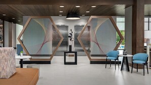 Eine moderne Lobby mit geometrischer Wandgestaltung, einem zentralen Kunstwerk und Sitzbereichen.