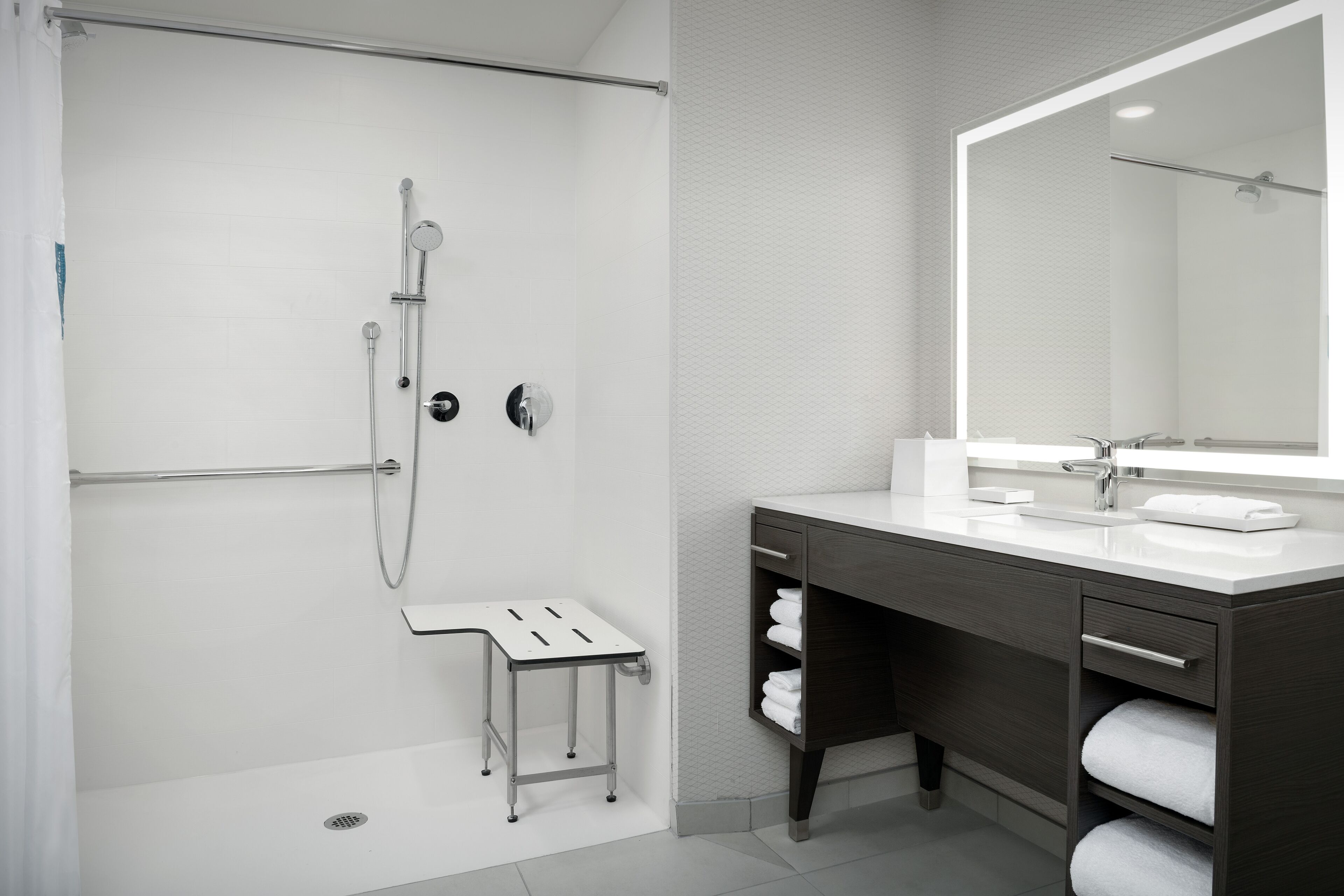 Une salle de bain moderne équipée d’une douche, d’un meuble-lavabo avec un miroir et d’un porte-serviettes.
