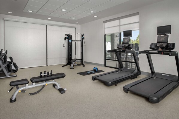 A modern gym with treadmills, a bench press, and a cable machine.