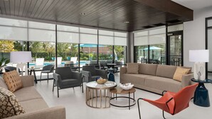 Ein moderner Innenraum mit Blick auf einen Pool, ausgestattet mit Sofas, Sesseln und Tischen.
