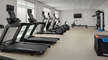 A gym with multiple treadmills, stationary bikes, and a rowing machine.